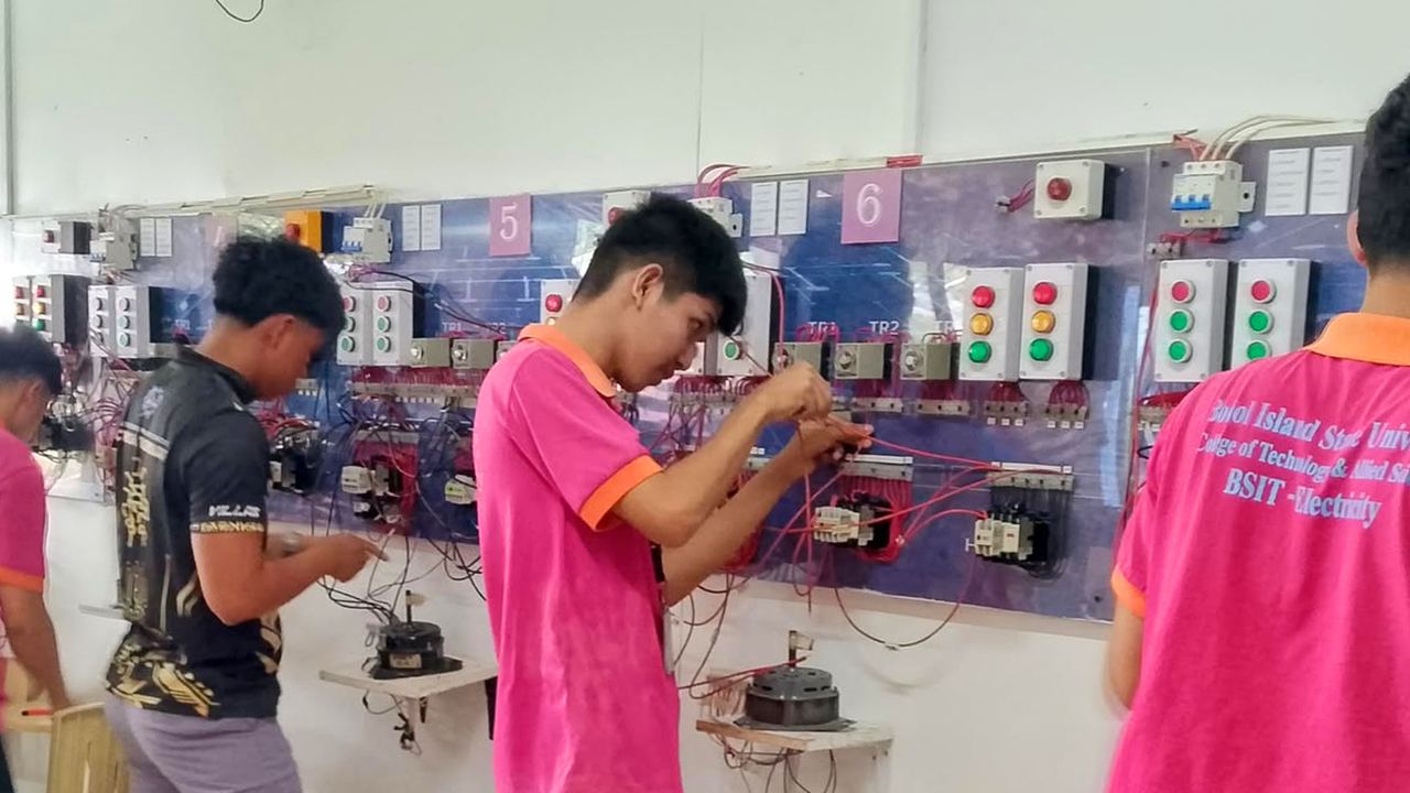 Students wiring motor control circuits at the panel boards in the electrical laboratory